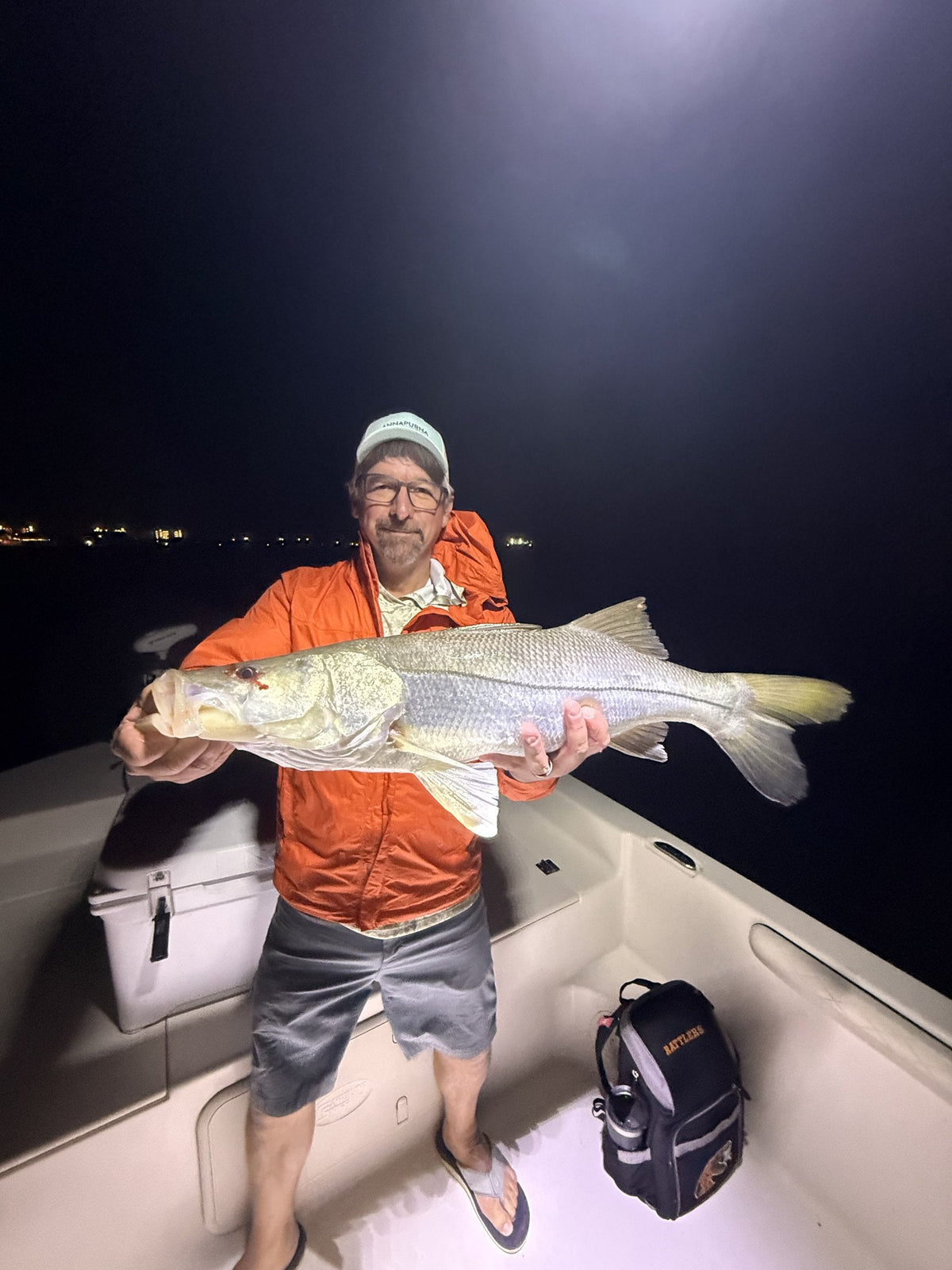 Angler holding a bull redfish under the boat lights at night