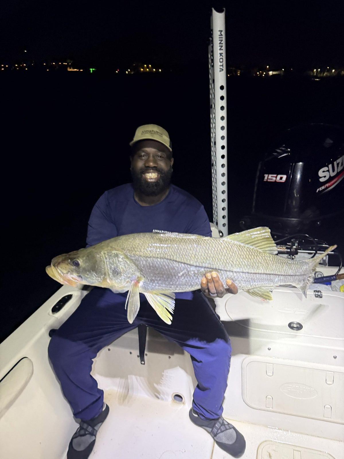 Smiling angler seated on the bow with a big night snook
